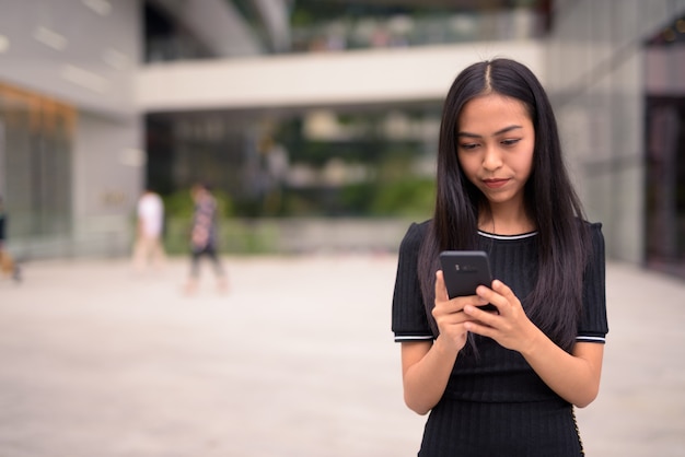 Giovane bella donna turistica asiatica utilizzando il telefono presso il centro commerciale all'aperto