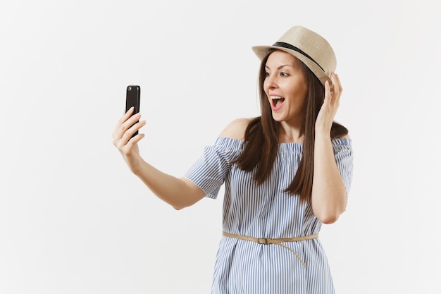 Giovane bella donna vestita vestito blu, cappello facendo selfie girato sul telefono cellulare o videochiamata isolato su sfondo bianco. Persone, emozioni sincere, concetto di stile di vita. Zona pubblicità. Copia spazio.