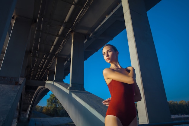 Giovane bella ginnasta della donna che posa sulla trave del ponte