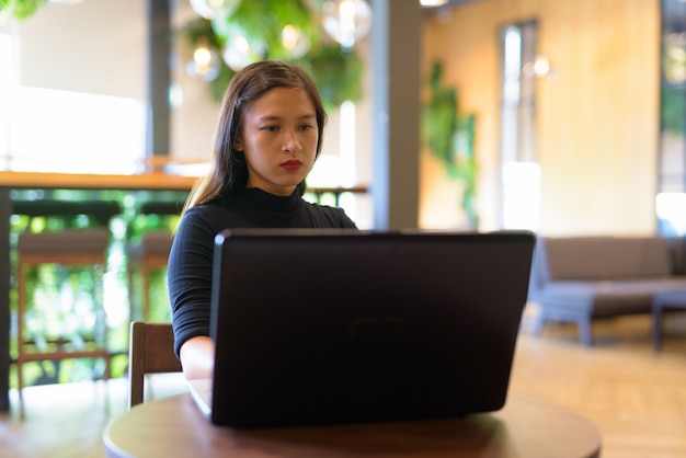 Giovane bella imprenditrice asiatica utilizzando laptop presso la caffetteria