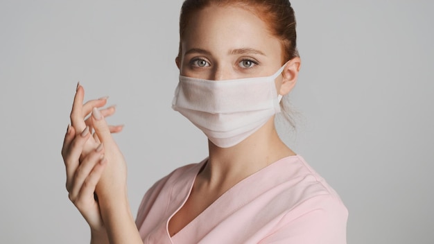 Giovane bella infermiera in maschera medica che si lava le mani sulla macchina fotografica isolata Il primo concetto di sicurezza
