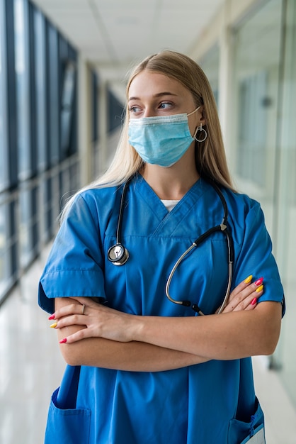 Giovane bella infermiera in piedi nel corridoio con una maschera. Concetto di medicina