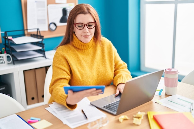 Giovane bella lavoratrice d'affari donna taglie forti che utilizza il touchpad e il computer portatile in ufficio