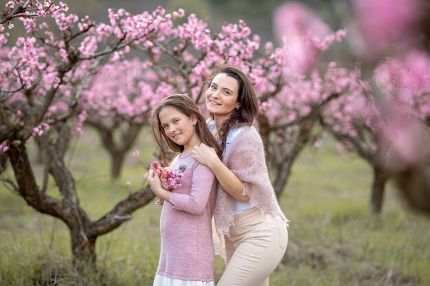 Giovane bella madre alla primavera, albero di fioritura rosa