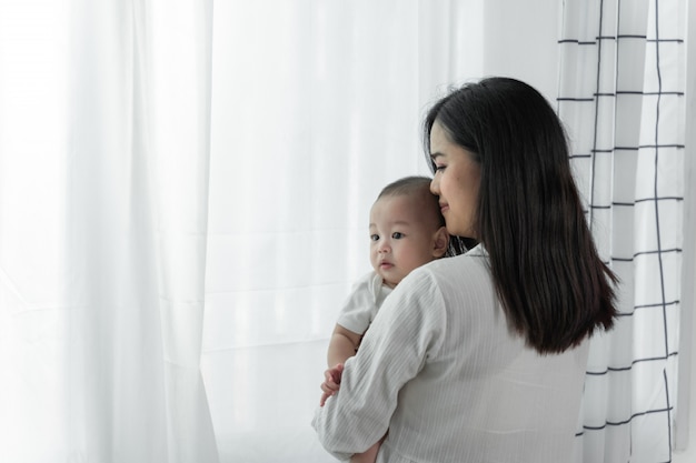 Giovane bella madre asiatica con il suo piccolo neonato sveglio a casa.