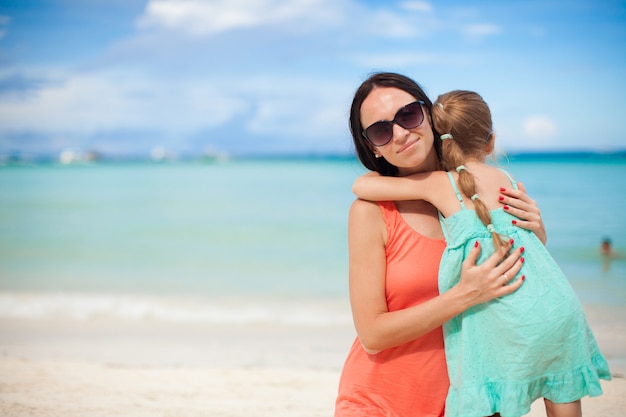 Giovane bella madre e la sua adorabile piccola figlia in spiaggia tropicale