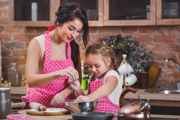 Giovane bella madre e sua figlia piccola cucinare insieme in cucina
