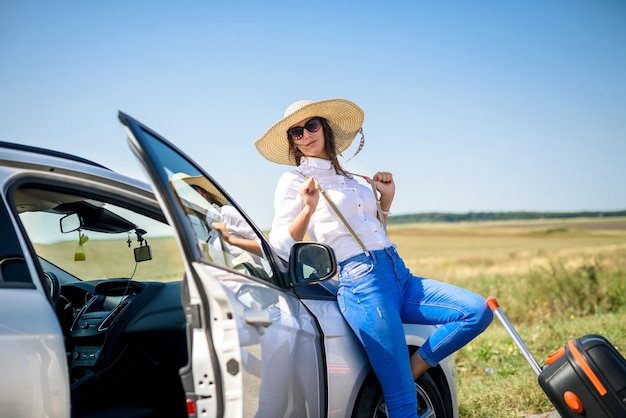 giovane bella modella felice vicino alla sua auto in viaggio estivo