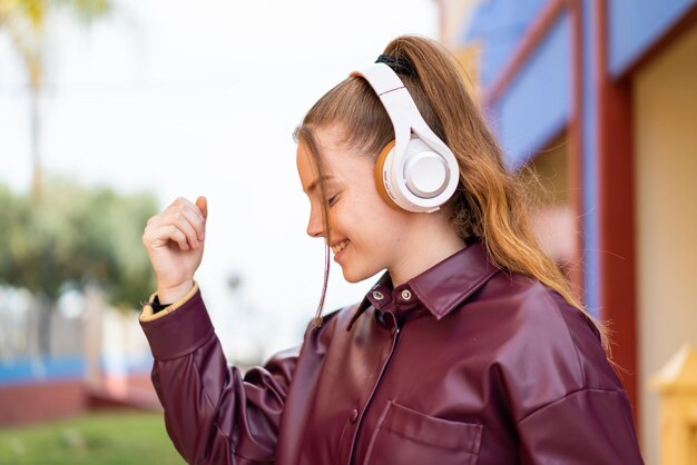 Giovane bella ragazza all'aperto ascoltando musica e ballando