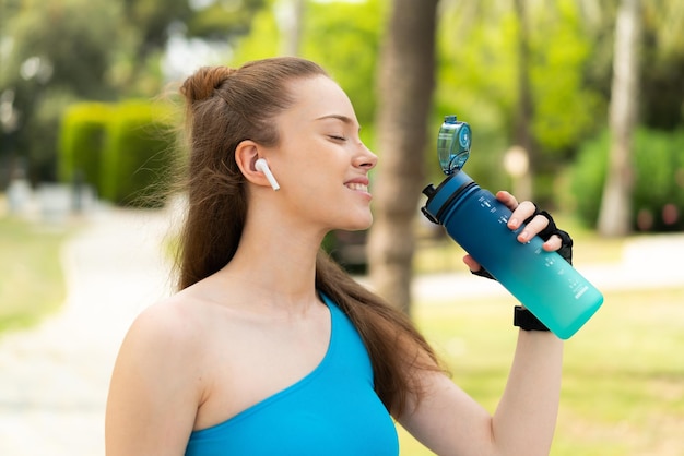 Giovane bella ragazza all'aperto che fa sport con una bottiglia d'acqua