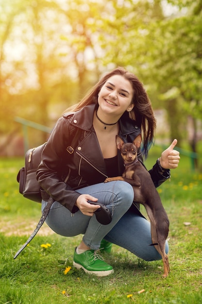 Giovane bella ragazza caucasica che gioca con il terrier di giocattolo russo del cane all&#39;aperto