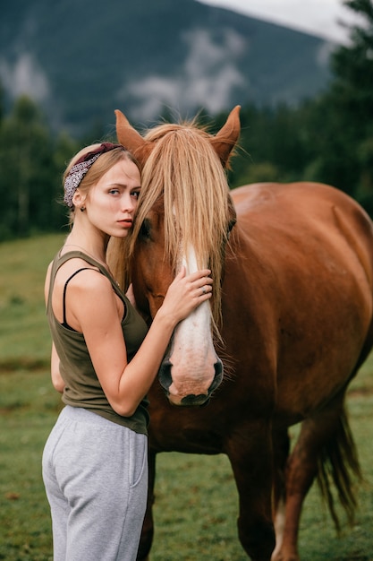 Giovane bella ragazza che abbraccia cavallo alla natura