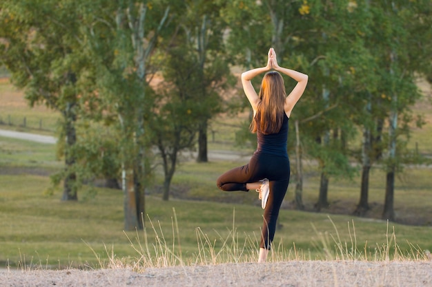 Giovane bella ragazza che fa yoga in natura.