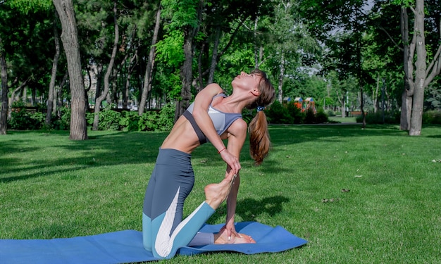 giovane bella ragazza che fa yoga su un prato verde