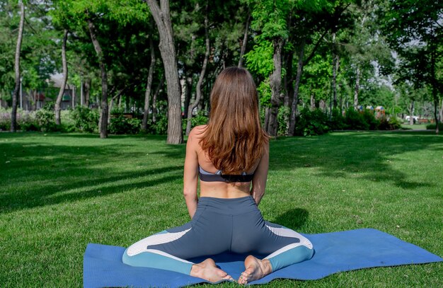 giovane bella ragazza che fa yoga su un prato verde