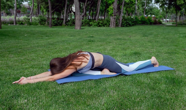 giovane bella ragazza che fa yoga su un prato verde