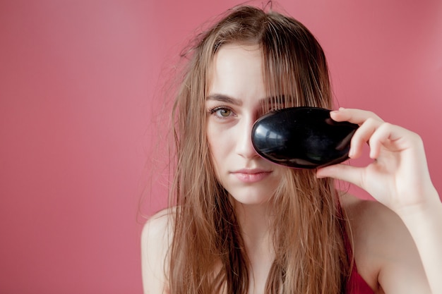 Giovane bella ragazza che ha problemi mentre capelli su sfondo rosa