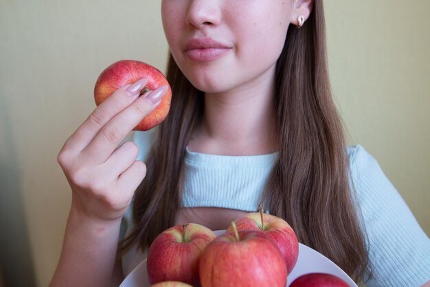 Giovane bella ragazza che mangia una mela in primo piano