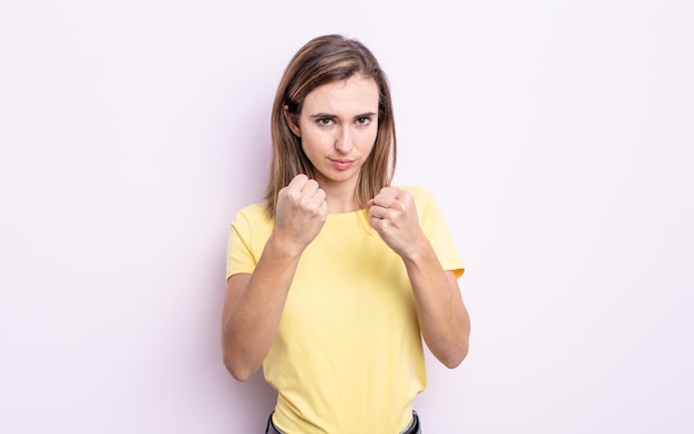 Giovane bella ragazza che sembra sicura di sé arrabbiata, forte e aggressiva con i pugni pronti a combattere in posizione di boxe