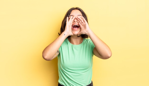 Giovane bella ragazza che si sente felice, eccitata e positiva, emette un grande grido con le mani vicino alla bocca, chiamando