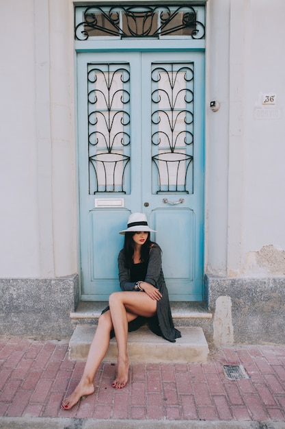 giovane bella ragazza con cappello in posa sullo sfondo di una porta d&#39;epoca