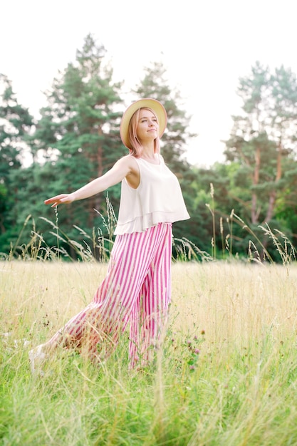 Giovane bella ragazza con i capelli rosa nel cappello estivo sulla radura