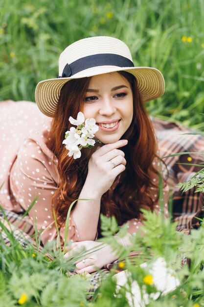 Giovane bella ragazza dai capelli rossi cammina in un frutteto di mele in fiore primaverile