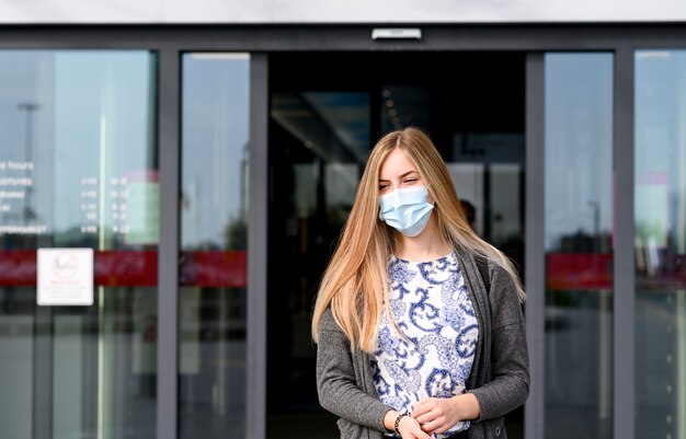 Giovane bella ragazza esce dal negozio con la maschera per il viso.