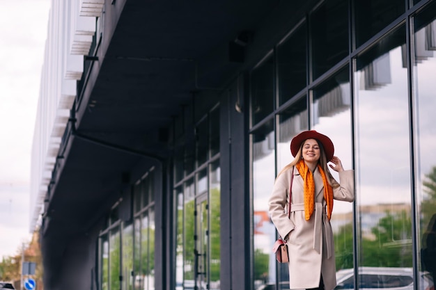 Giovane bella ragazza in abiti eleganti alla moda che cammina per le strade della città