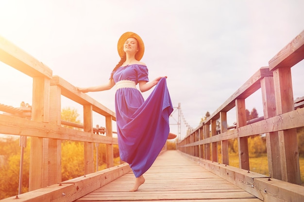 Giovane bella ragazza in abiti sulla natura. Una ragazza con un cappello cammina nel parco. Giovane donna su un picnic con un cesto fuori città.