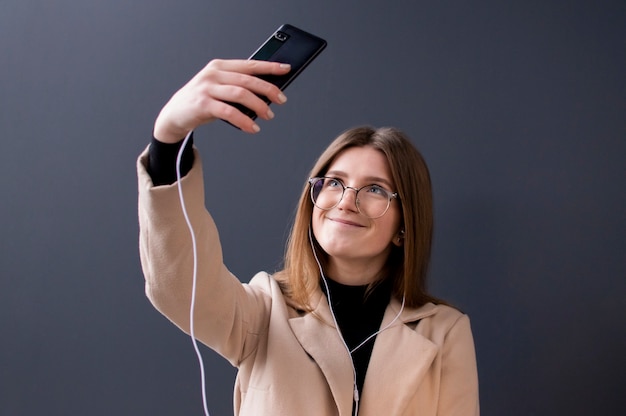 Giovane bella ragazza in occhiali prendendo un selfie