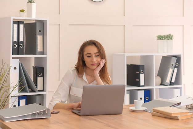 Giovane bella ragazza in ufficio lavora al computer