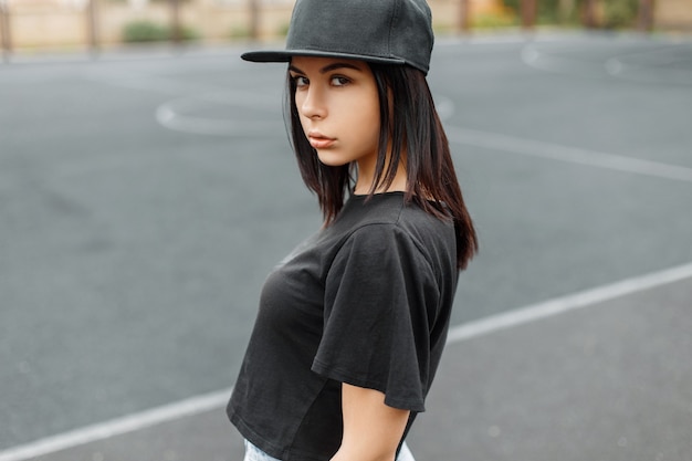 Giovane bella ragazza in un berretto da baseball nero e t-shirtthe stadio.