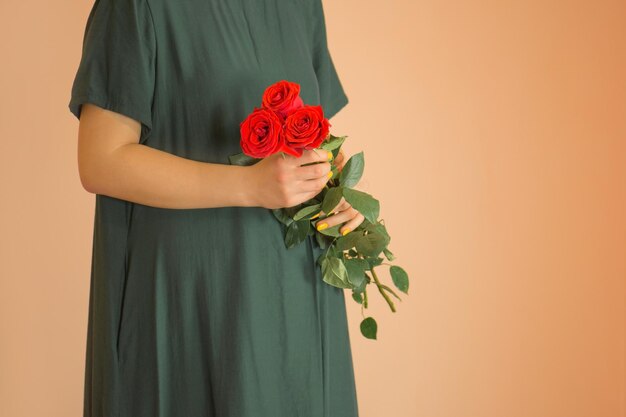 Giovane bella ragazza in un vestito verde lungo rigoroso modesto discreto con rose rosse Ragazza con bouquet di rose rosse