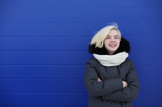 Giovane bella ragazza in una passeggiata in inverno sullo sfondo della parete blu