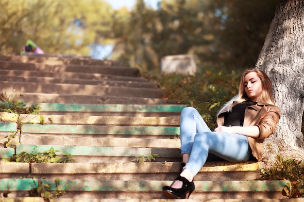 Giovane bella ragazza in una passeggiata nel parco autunnale. Caduta delle foglie nel parco cittadino. Ottobre.