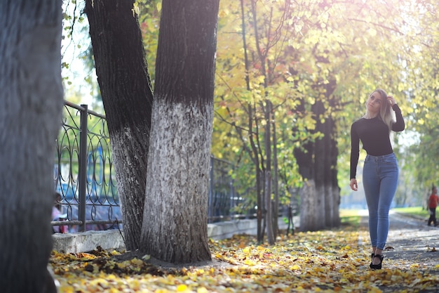Giovane bella ragazza per una passeggiata in un parco estivo. Caduta delle foglie nel parco cittadino. Inizio autunno. Settembre.