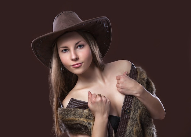 Giovane bella ragazza sexy in gilet di pelliccia e cappello da cowboy