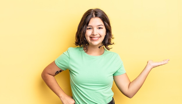 giovane bella ragazza sorridente, sicura di sé, di successo e felice, mostrando un concetto o un'idea sullo spazio della copia sul lato