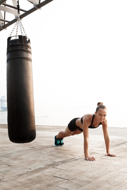 Giovane bella ragazza sportiva formazione boxe in riva al mare.