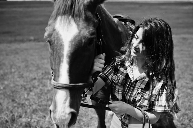 Giovane bella ragazza stare con il cavallo su un campo in una giornata di sole