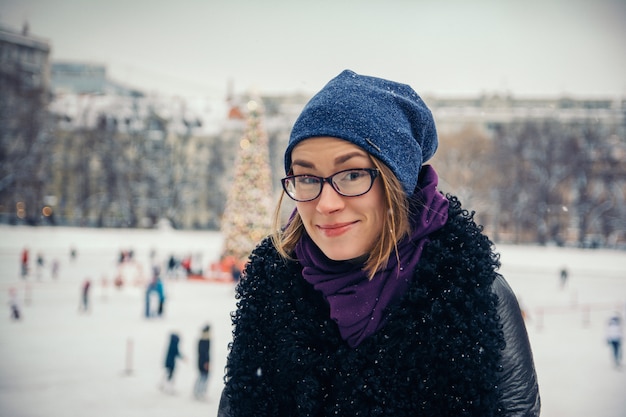 Giovane bella ragazza sulla strada in inverno sullo sfondo di decorazioni natalizie