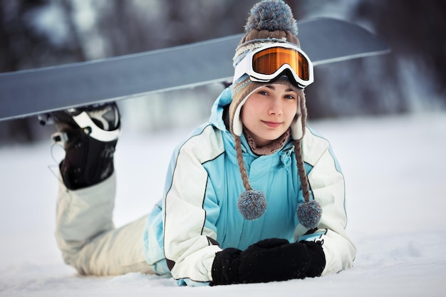 Giovane bella snowboarder femminile che riposa sulla pista da sci