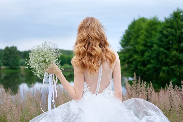 Giovane bella sposa in abito da sposa bianco all'aperto