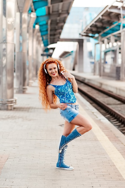 Giovane bella studentessa indossando una camicia a scacchi cuffie e uno zaino appoggiato sulla strada