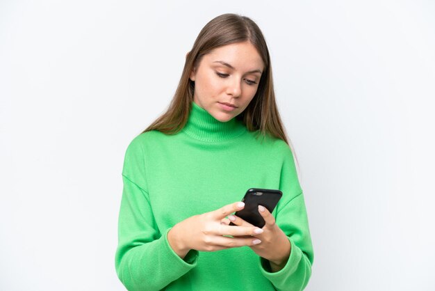 Giovane bellissima donna bionda isolata su sfondo bianco che manda un messaggio con il cellulare