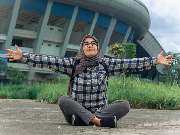 giovane bellissima ragazza musulmana musulmana che indossa l'hijab e seduta a terra nel parco e che respira