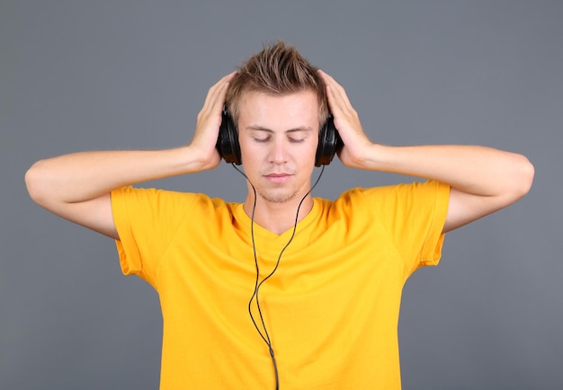 Giovane bello che ascolta la musica su sfondo grigio