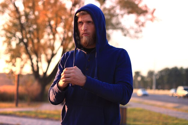 Giovane bello che fa esercizi di stretching prima di correre stando in piedi all'aperto