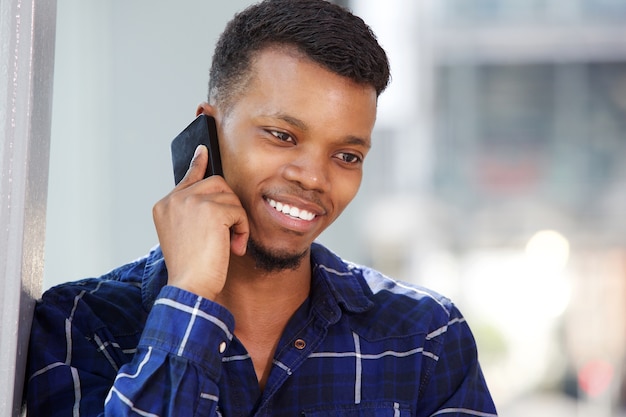 Giovane bello che parla sul sorridere del telefono cellulare